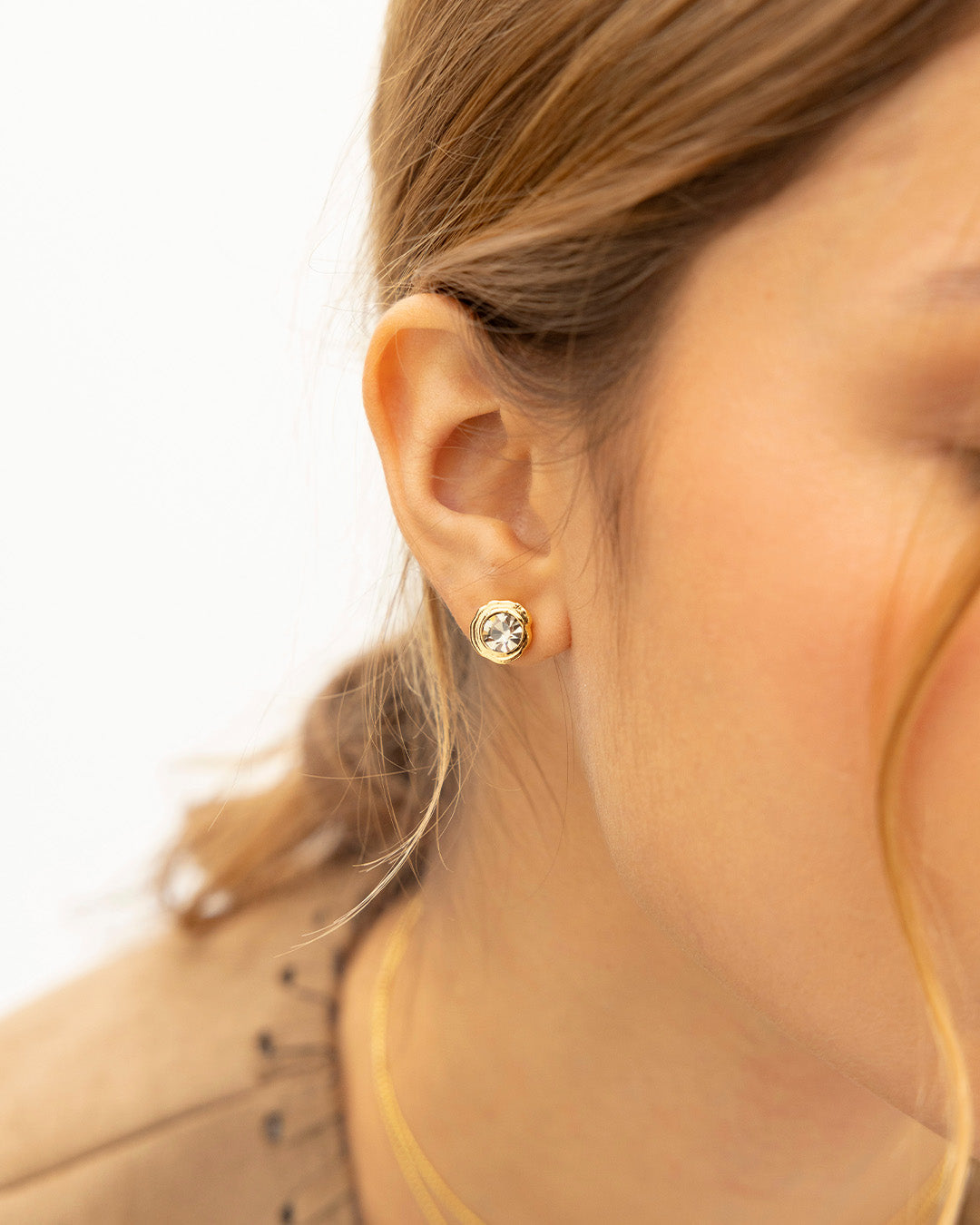 Acercamiento a oreja de mujer luciendo el set de collar Cristales con dije cristal y par de topos