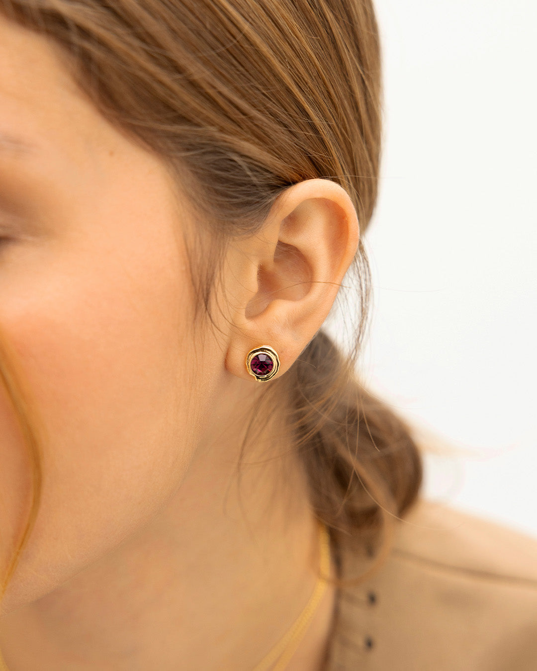 Oreja de mujer luciendo el par de topos cristal púrpura